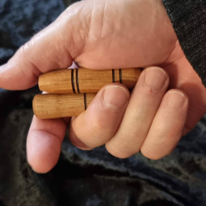 A person's hand wielding the Wooden Sensory Sticks Set.