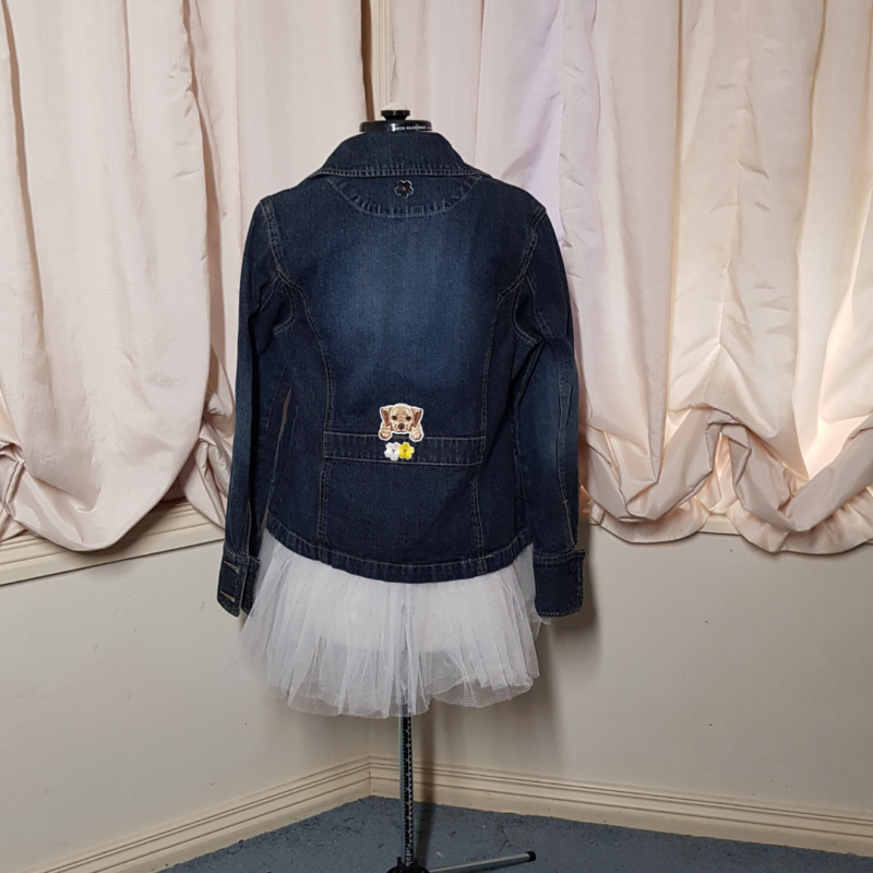 A Puppy Flower Power Upcycled Denim Jacket on a mannequin in front of a window.