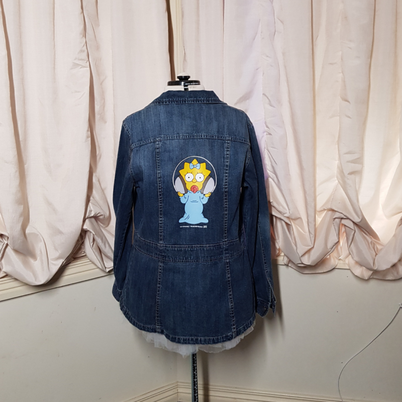 An upcycled Maggie Simpson Upcycled Denim Jacket featuring a teddy bear.